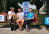 Andrzej Surdyk wraz z dwoma redaktorami siedzą na ławce na terenie dworca PKP w Skokach