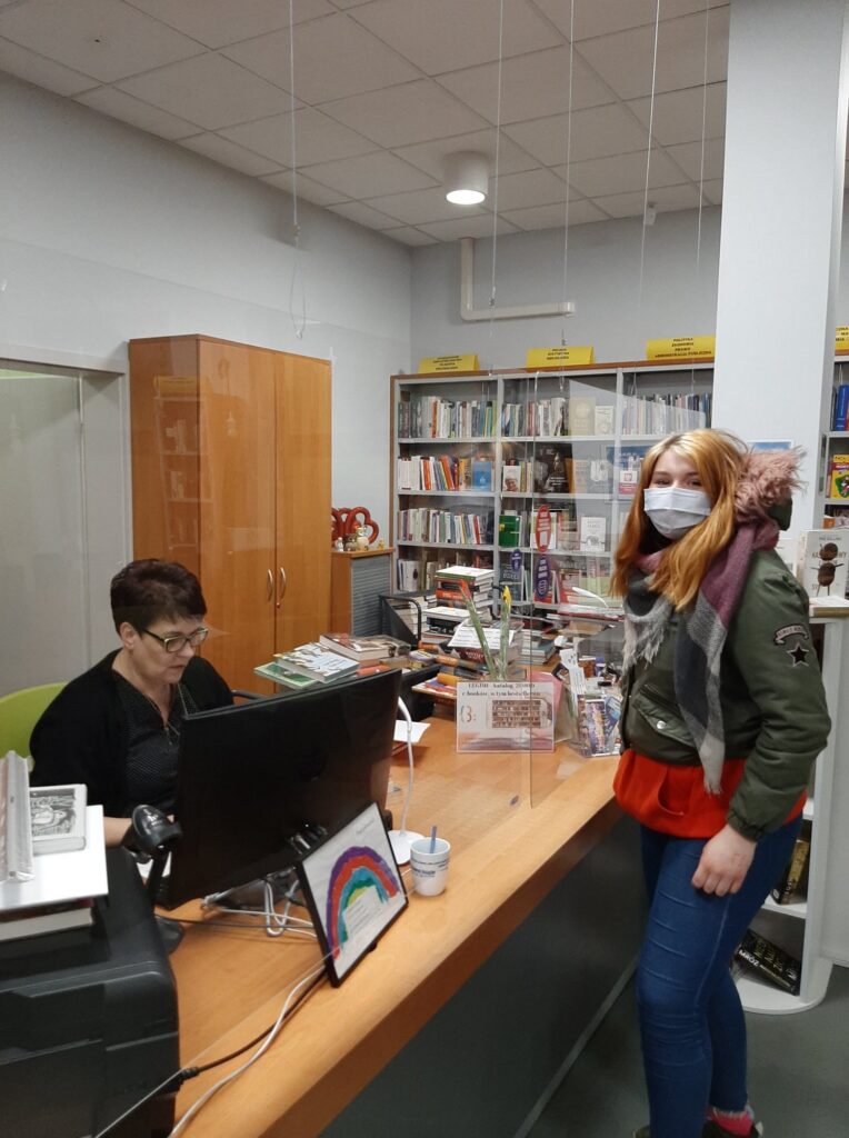 kobieta wypożycza książki w bibliotece