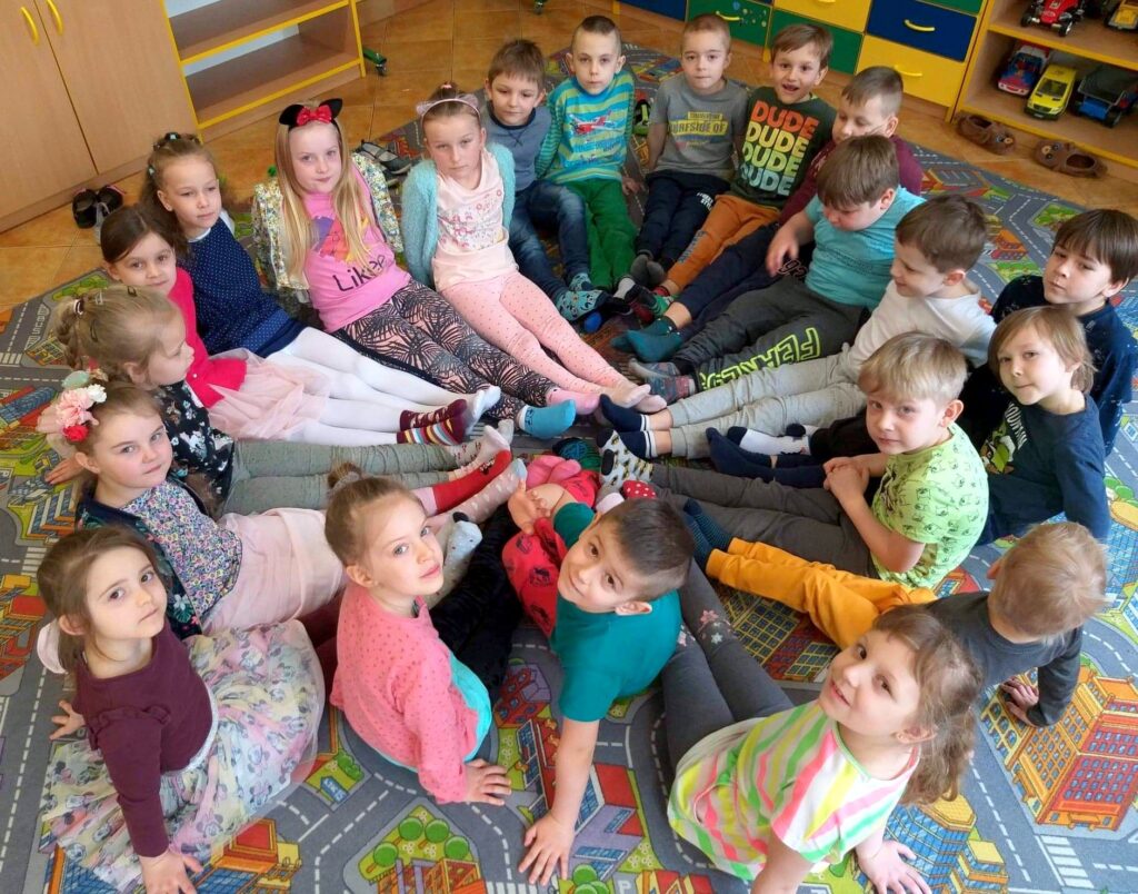 Dzieci w przedszkolu z różnokolorowymi skarpetkami na nogach obchodzą Światowy Dzień Zespoły Downa