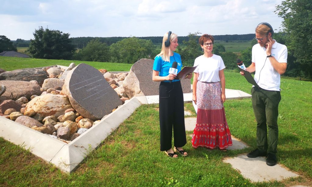 Pani Iwona Migasiewicz udziela wywiadu do mikrofonu dwóm redaktorom przy cmentarzu żydowskim - Kirkucie - w Skokach