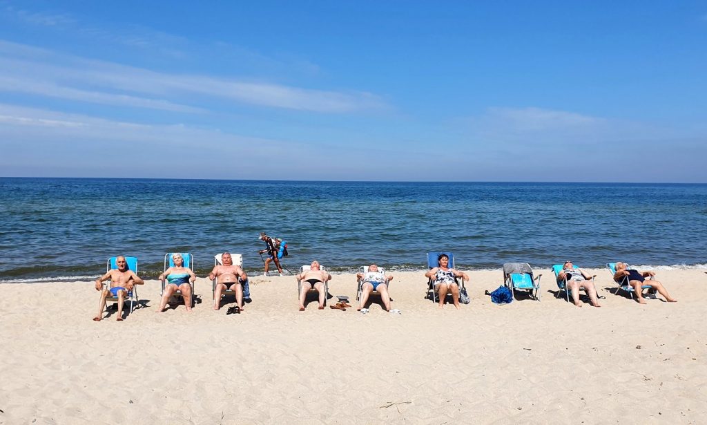 osoby leżą na leżakach na plaży w tle morze 