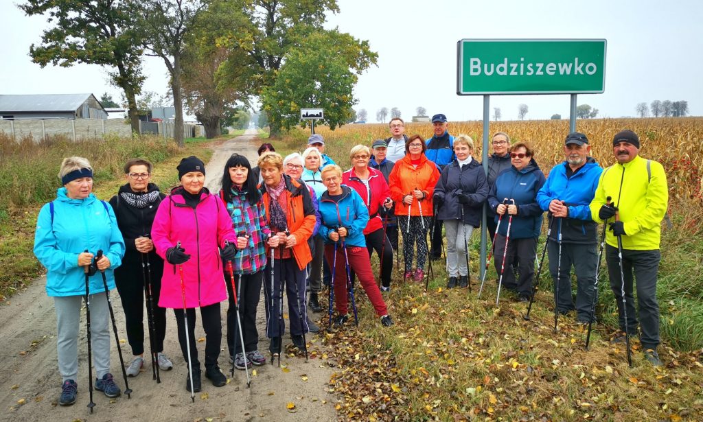 ok 20 piechurów z kijkami nordic walking stoi przy tablicy Budziszewko