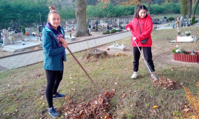 wolontariusze-na-cmentarzu-4 2 uczennice grabią liście na cmentarzu